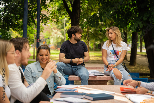 A diverse group of university students collaborates in the campus yard, exchanging ideas and studying together.