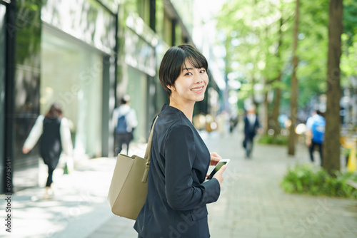 ビジネス街を歩く30代女性会社員,笑顔 photo