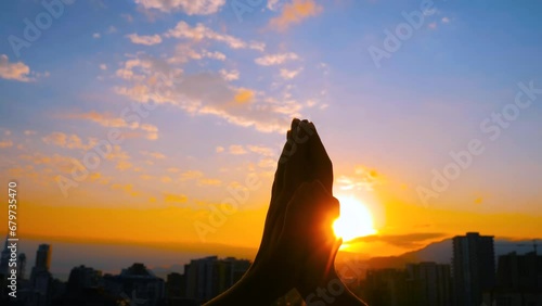Close up view: silhouette of woman is lifting hands up, doing stretching and yoga exercises against the sunset, sunrise sky - sun salutation, sun lens flares. Fitness, sport and freedom concept photo