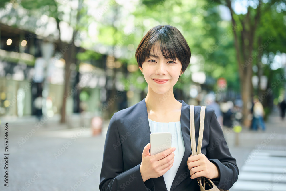 街中でスマートフォンを確認する30代女性会社員,笑顔