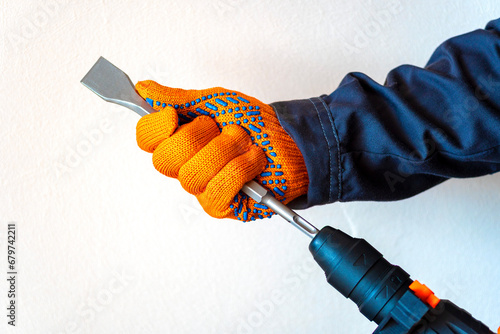 hands in protective gloves, hammer drill, chisel, bit, photo