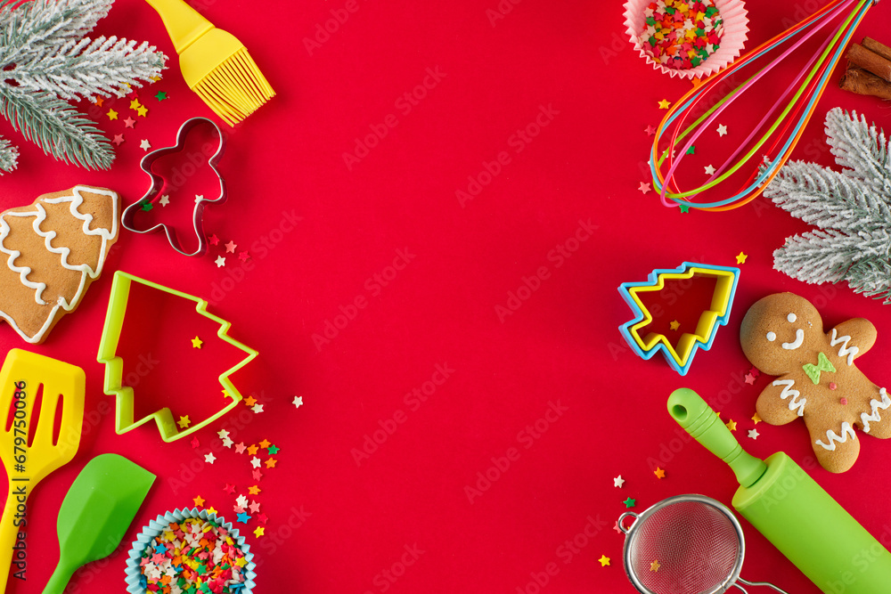 Making holiday goodies concept. Top view flat lay of gingerbread cookies, candies, baking equipment, baking molds, frosty fir twigs, stars on red background with promo slot