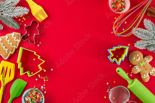 Making holiday goodies concept. Top view flat lay of gingerbread cookies, candies, baking equipment, baking molds, frosty fir twigs, stars on red background with promo slot