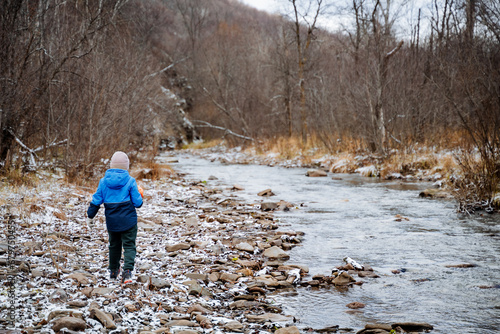 A boy in an autumn forest walks alone along the river bank, a walk in a mountainous area, the first snow, a child walks in nature.