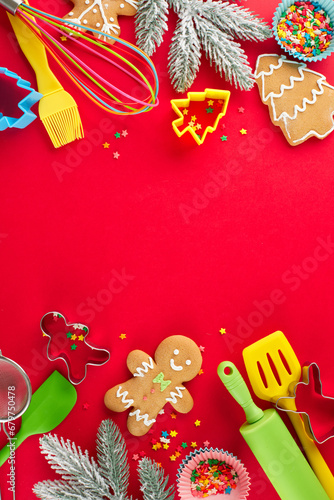 Baking festive snacks concept. Top view vertical flat lay of sweet cookies, candies, baking tools, baking tins, frosty fir twigs, stars on red background with advert zone