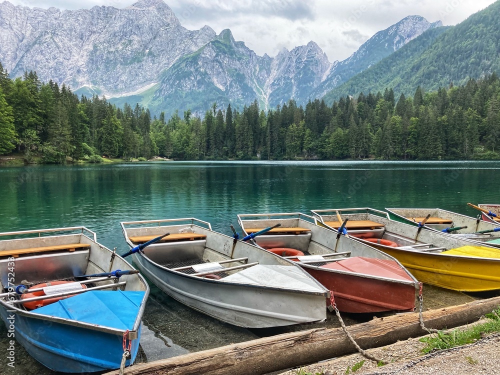 Rowing boats waiting for tourists to rent at the emerals lake of the Lago Inferiore di Fusine in the Julian alps in the North of Italy close to the border with Slovenia
