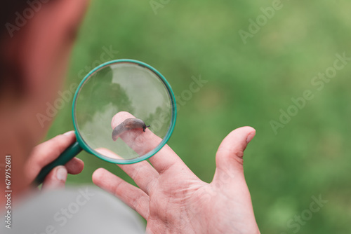 Connecting kids and nature concept. Young boy examine through magnifying glass a slug