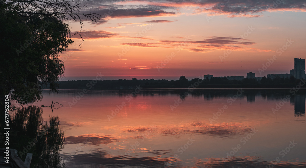 Sunrise on lake with cloudy sky and calm mirror water surface. Colorful morning by the river