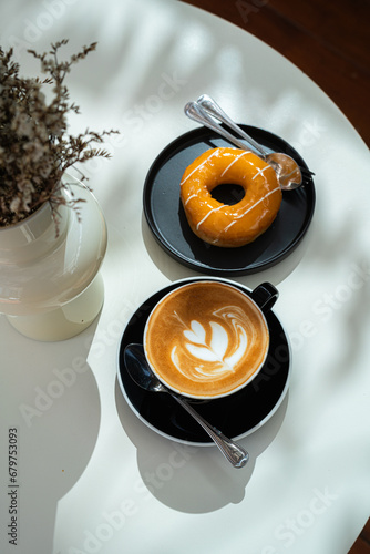 Obraz na płótnie Hot coffee latte with latte art milk foam in cup mug and Homemade Orange Donut wood desk on wood desk on top view. As breakfast In a coffee shop at the cafe,during business work concept w salonie