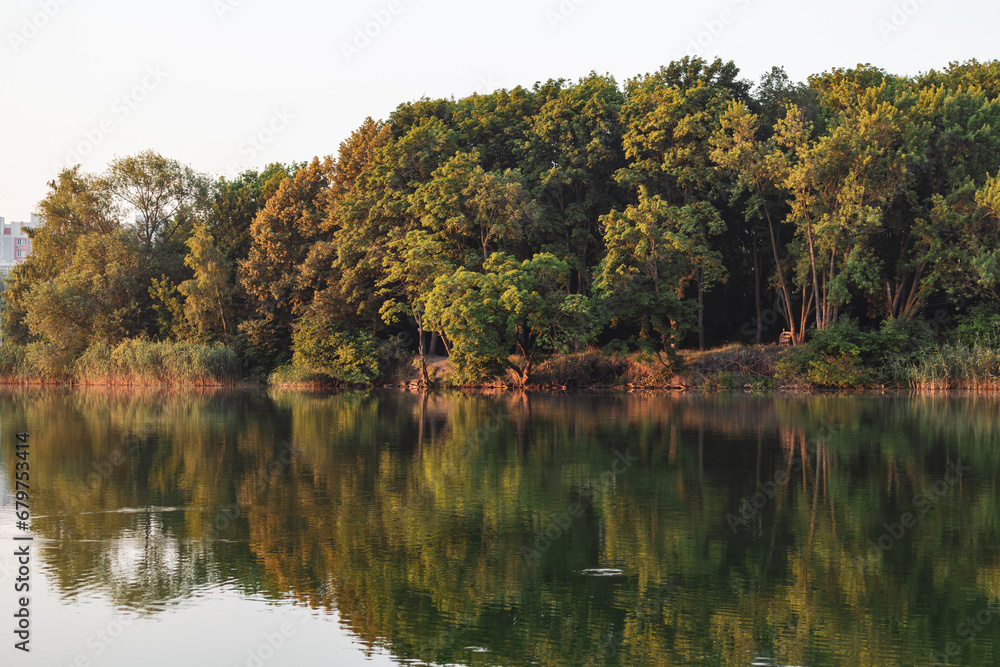 Calm sunrise, dawn on river with forest reflection on mirror water. Trees and reeds in warm sunlight, nature Calm sunrise, dawn on river with forest reflection on mirror water. Trees and reeds in warm sunlight, nature