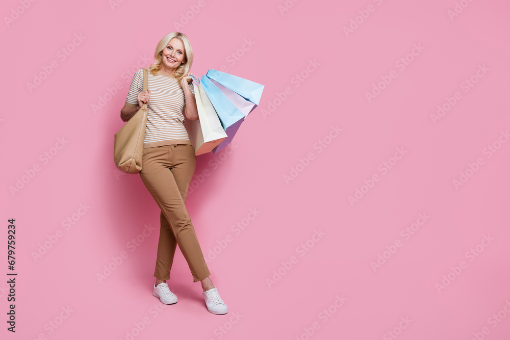 Full length photo of gorgeous cute lady dressed stylish outfit standing empty space billboard isolated on pink color background Full length photo of gorgeous cute lady dressed stylish outfit standing empty space billboard isolated on pink color background