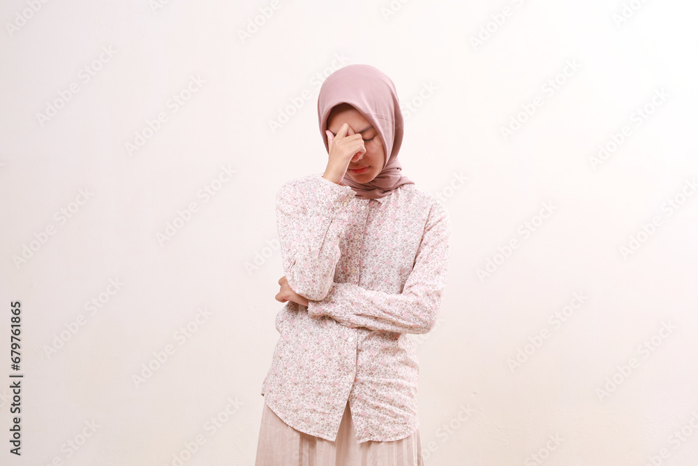Stressed young asian muslim woman standing while holding her head. Isolated on white background Stressed young asian muslim woman standing while holding her head. Isolated on white background