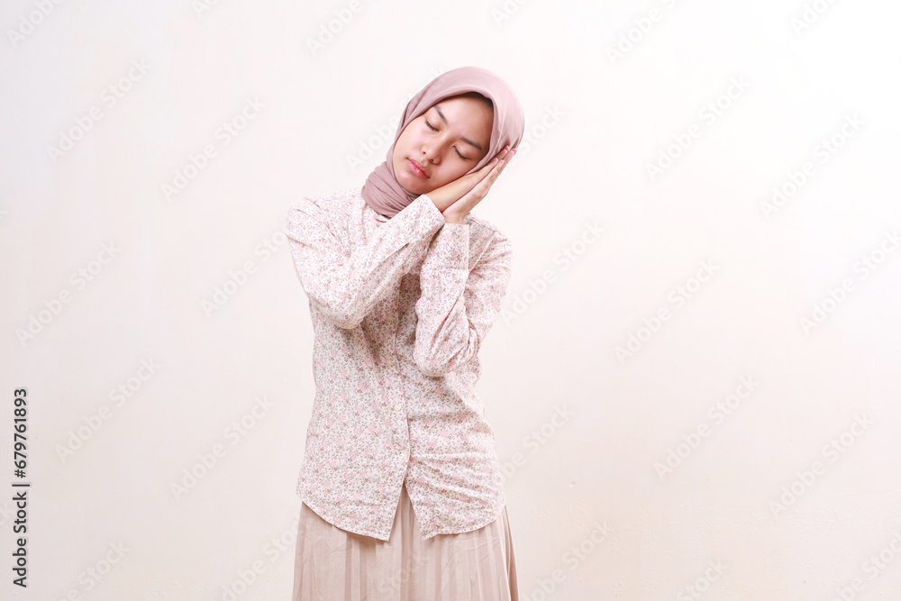 Young asian muslim girl standing while showing sleep gesture. Isolated on white background Young asian muslim girl standing while showing sleep gesture. Isolated on white background