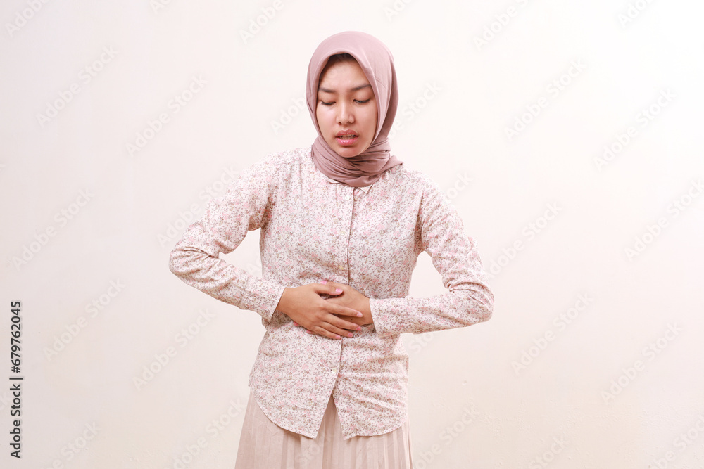 Young asian muslim woman feeling painful with her stomach. Menstrual pain concept. Isolated on white Young asian muslim woman feeling painful with her stomach. Menstrual pain concept. Isolated on white