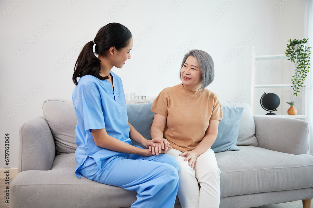 caregiver or nursing home holding hands and talking with senior woman on sofa caregiver or nursing home holding hands and talking with senior woman on sofa