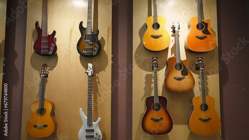 Electric and classical wooden acoustic guitars hanging on the showcase wall in a musical instrument store