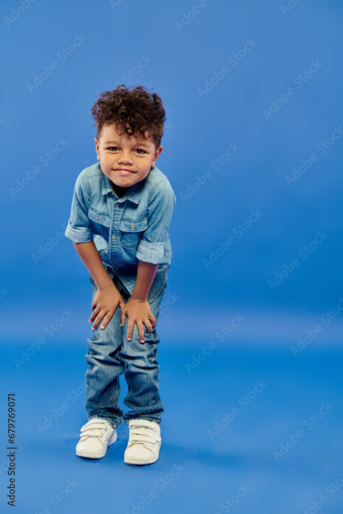 little curly african american preschooler boy in stylish denim outfit posing on blue background little curly african american preschooler boy in stylish denim outfit posing on blue background