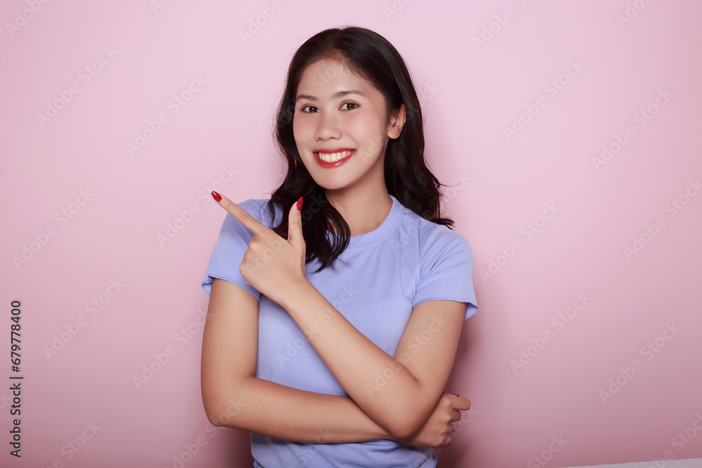 Standing and pointing happily, Portrait of a beautiful young woman in a light pink background, happy and smile, posting in stand position, Portrait of a friendly young woman smiling happily. Standing and pointing happily, Portrait of a beautiful young woman in a light pink background, happy and smile, posting in stand position, Portrait of a friendly young woman smiling happily.