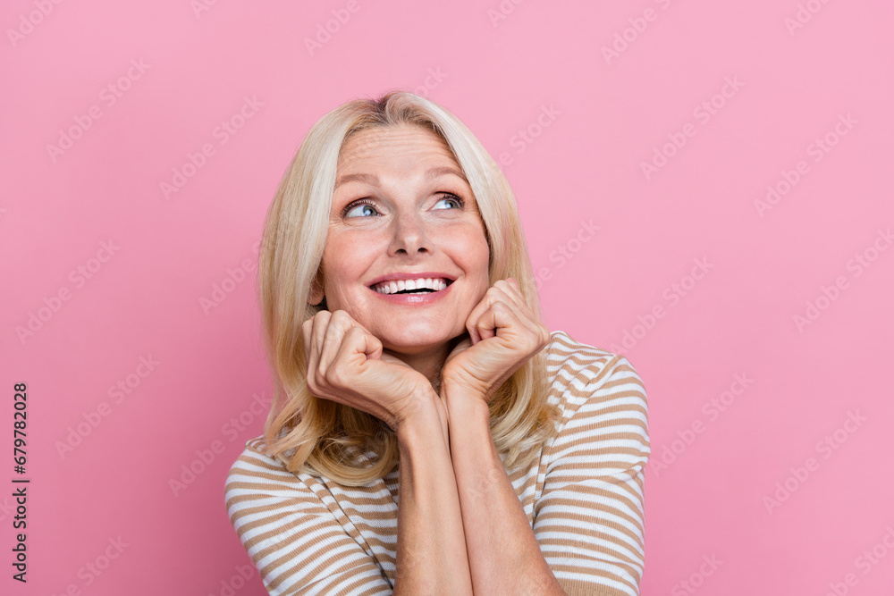 Portrait of dreamy woman wear trendy clothes holding hands on cheekbones look at offer empty space isolated on pink color background Portrait of dreamy woman wear trendy clothes holding hands on cheekbones look at offer empty space isolated on pink color background
