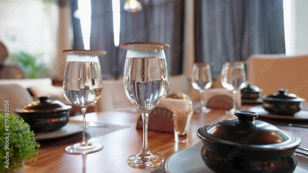 Close up of restaurant table served with glasses of water and black ceramic soup pots Close up of restaurant table served with glasses of water and black ceramic soup pots