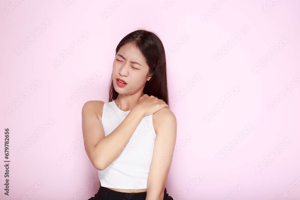 Portrait of a young woman in a light pink background, Asian woman experiencing pain in her body. Portrait of a young woman in a light pink background, Asian woman experiencing pain in her body.