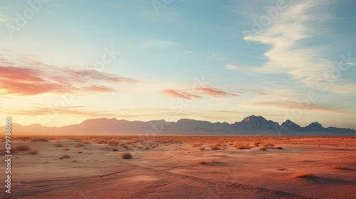  a view of a desert with mountains in the distance and a sunset in the middle of the desert with a few clouds in the sky.