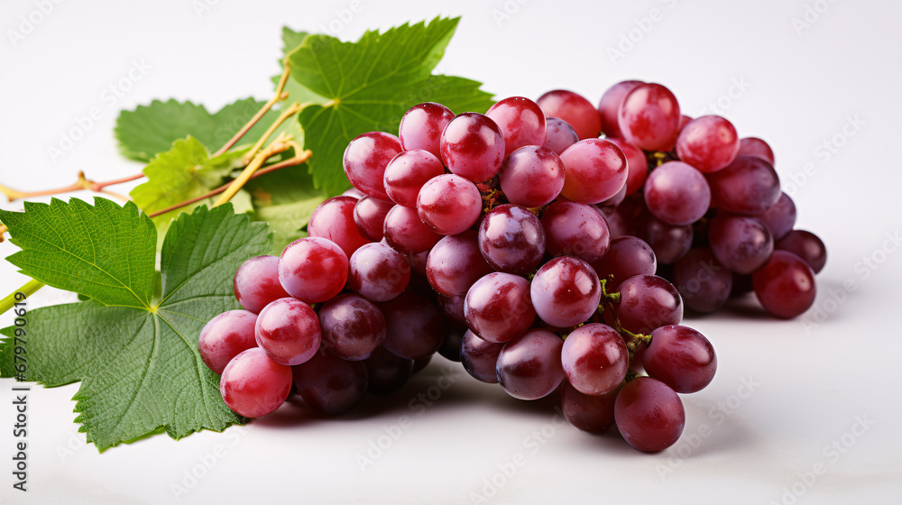 Isolated green-leafed, partially-cut red grapes on a white backdrop.