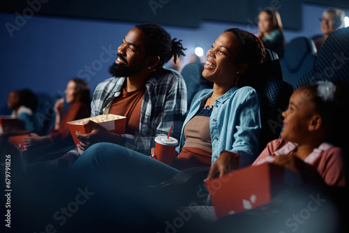 Happy black family enjoying in watching movie in cinema. photo