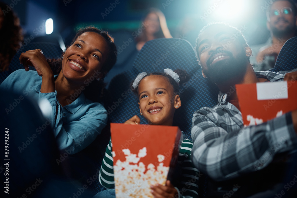 Obraz premium Happy African American family enjoys in movie projection in theater.