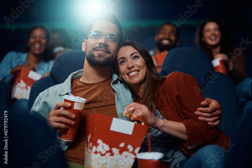 Happy woman and her boyfriend enjoying in movie projection in theater. photo