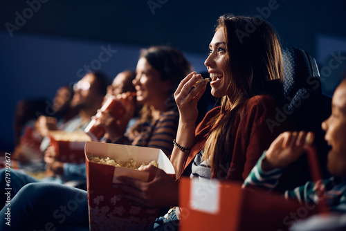 Cheerful woman eating popcorn during comedy movie in cinema. photo