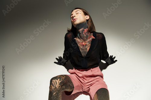 Fototapeta Naklejka Na Ścianę i Meble -  good looking young man with tattoos and piercing posing on floor with closed eyes, fashion concept