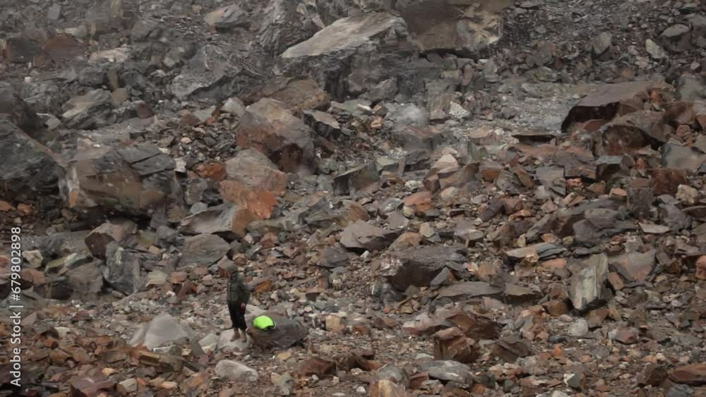 Caucasian male tourist standing at the foot of the cliff covered by huge sharp stones at winter day under falling snow filmed in slow motion. Man travels to Svaneti glacier in Georgia. Enjoy nature Caucasian male tourist standing at the foot of the cliff covered by huge sharp stones at winter day under falling snow filmed in slow motion. Man travels to Svaneti glacier in Georgia. Enjoy nature