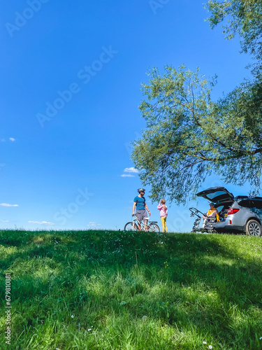 happy family outdoors father teaching daughter yo bicycle mother sitting in car trunk
