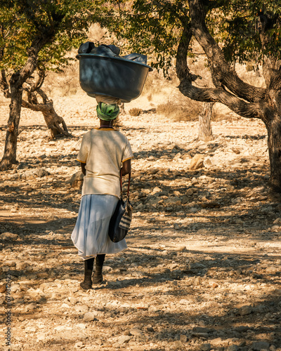 Local woman carryng home washed clothes on her head, Epupa Falls, Kunene Region, Namibia. photo