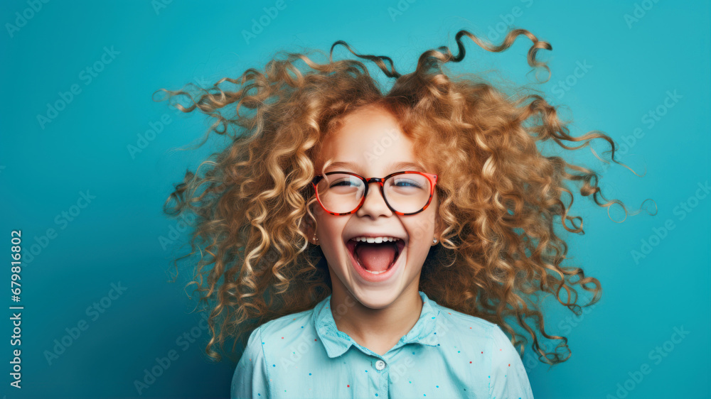 Portrait of a cute little girl with curly hair and glasses on a blue background