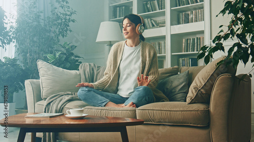 Portrait of young woman relaxing at home and listening music. Girl sitting on sofa. Relaxation, Meditation and Mindfulness photo