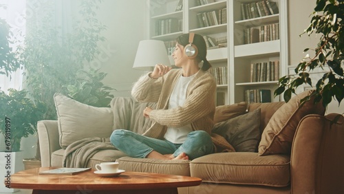 Portrait of young woman relaxing at home and listening music. Girl sitting on sofa. Relaxation, Meditation and Mindfulness