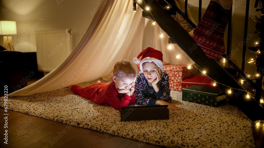 Two boy watching video on tablet computer while waiting for Christmas or New Year. Winter holidays, celebrations and party.