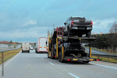 Car carrier trailer truck with brand new SUV cars for sale. New car delivery and shipping. Car transporter trailer loaded with many new cars for the customers. Two-level modular hydraulic semi-trailer