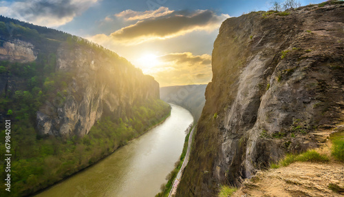 long river between huge cliff with ground texture and background wide view with the sun at the edge of view