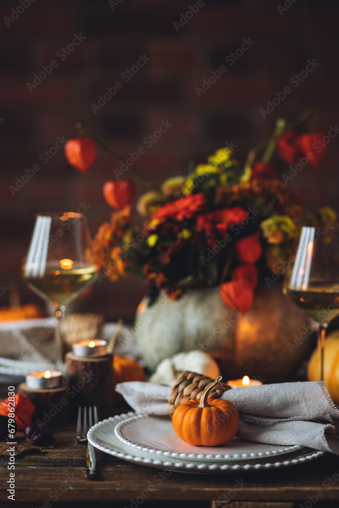 Elegant atmospheric beautiful dinner table setting for thanksgiving or wedding celebration, fall countryside style, pumpkins as decor. Romantic cozy home atmosphere. Wine, floral pumpkin centrepiece.