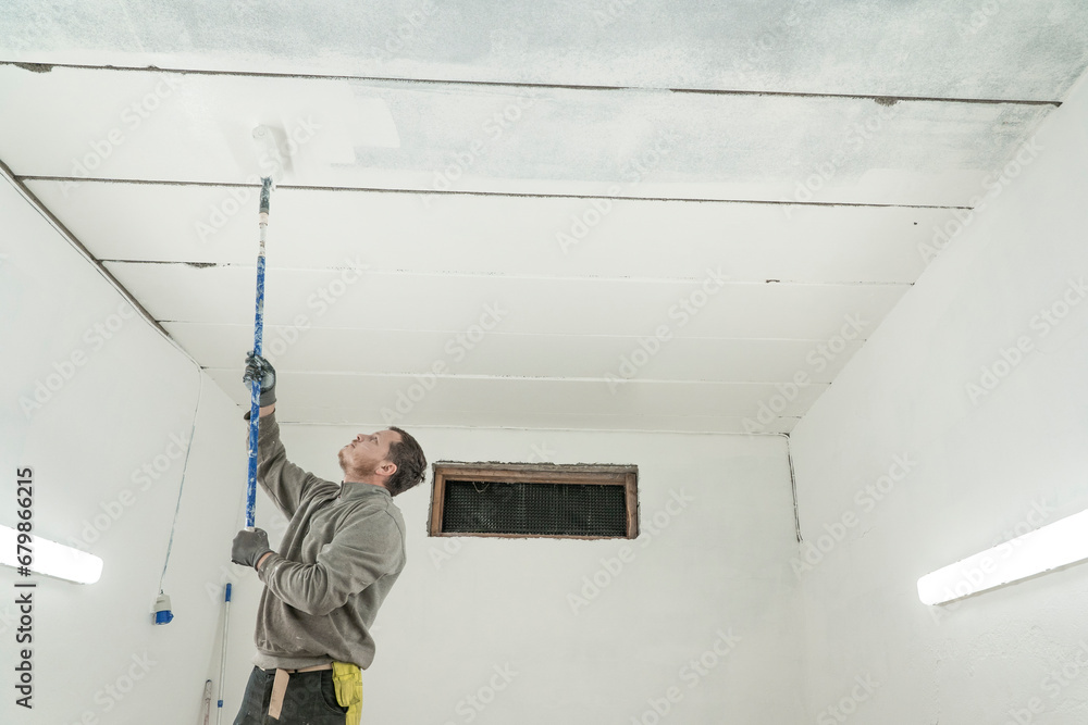 Masterful Room Transformation: Skilled Man Paints Spacious Interior with Expert Precision.