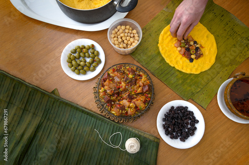 Hechura de hallacas andinas venezolanas. Se preparan con masa de harina de maíz, guiso crudo de carne de res, pollo y cerdo, aceitunas o alcaparras, pasas y garbanzos. Se envuelven en hojas de plátano photo