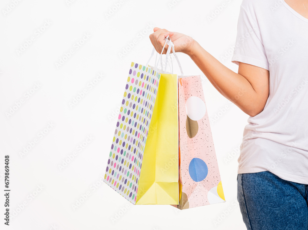 Closeup female holds in hand with multicolor clear empty blank craft paper gift bag, women hand holding colorful shopping bag many packets isolated on white background, shopping day concept