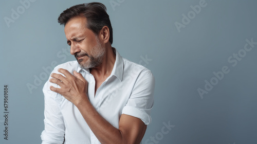 diseases and illnesses - man with face distorted in pain holds one hand at his neck,shoulder or upper arm photo