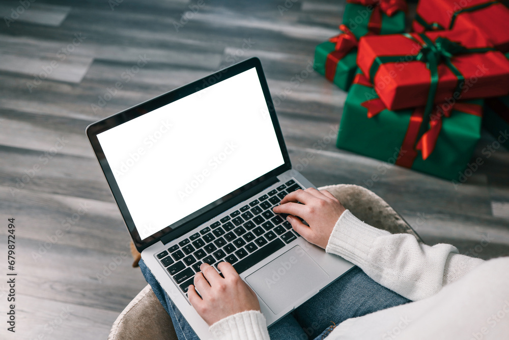 Young woman work on laptop computer with blank display screen with mockup copy space. Modern home living room interior design. Christmas, New Year decorated workspace Young woman work on laptop computer with blank display screen with mockup copy space. Modern home living room interior design. Christmas, New Year decorated workspace
