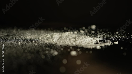 Macro close up at moving crushed drug cocaine powder substance. Opioid crises abuse and addiction. Hard addictive illegal drugs. photo