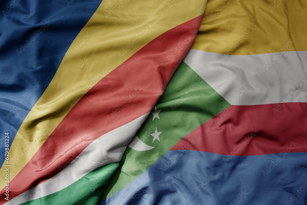 big waving national colorful flag of seychelles and national flag of comoros .