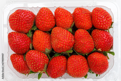 Red ripe strawberries with green stems in plastic tray container with the lid open isolated on white background. Top view
